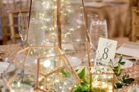 24 a pretty modern winter wedding centerpiece of faceted candle lanterns with lights and greenery is a cool and bold idea