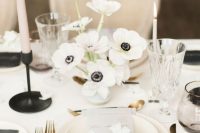 27 a stylish modern winter wedding tablescape with a white anemone centerpiece, neutral porcelain and a floral menu, black candleholders and cutlery