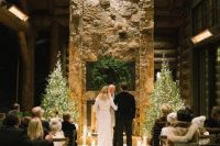 29 a stone fireplace, candles, an evergreen wreath and a couple of lit up Christmas trees on the sides is a great idea for a holiday wedding