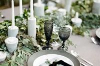 31 grey plates and grey concrete candleholders, grey linens and a lush greenery runner for a refined modern wedding tablescape