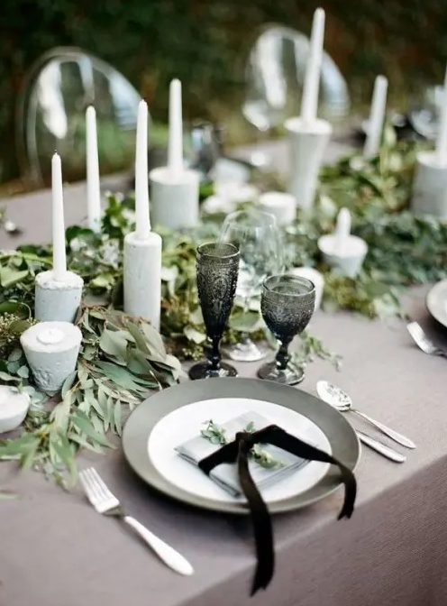 grey plates and grey concrete candleholders, grey linens and a lush greenery runner for a refined modern wedding tablescape