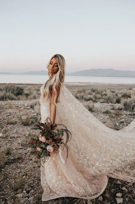 a beautiful blush A-line wedding dress with a train and a super long capelet, with white stars embroidered is a gorgeous idea
