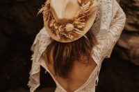 a boho bridal look with  boho lace A-line wedding dress with a cutout back and bell sleeves, a tan hat with dried blooms and grass
