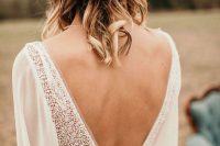 a boho folk bridal look with a flowy semi sheer and boho lace wedding dress plus a tan hat decorated with greenery and flowers