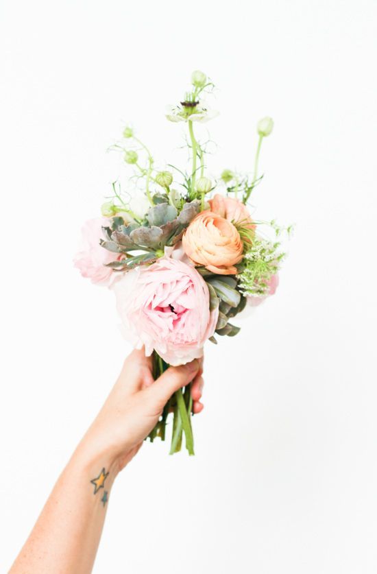 a bright wedding bouquet of peachy and pink blooms, greenery and a succulent is a cool solution for a summer wedding