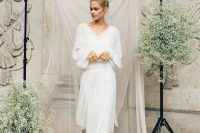 a flowy oversized sweater with a deep V-neckline, a tulle midi skirt, white shoes and a top knot for a girlish yet casual winter bridal look