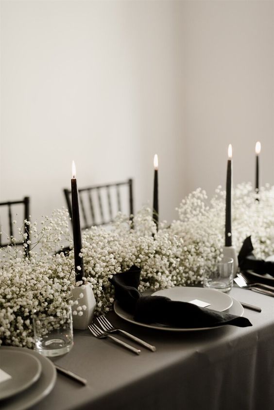 a gorgeous monochromatic wedding centerpiece of white baby's breath, black candles in white candleholders is ideal for a minimalist wedding