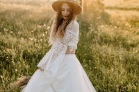 a hippie bridal look with a boho lace crop top, a tulle maxi skirt, a tan hat with greenery decor is a chic adn cool solution