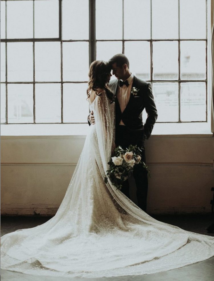 a lace A-line wedding dress paired with a gorgeous fully embellished sheer capelet with a train for a glam and chic look