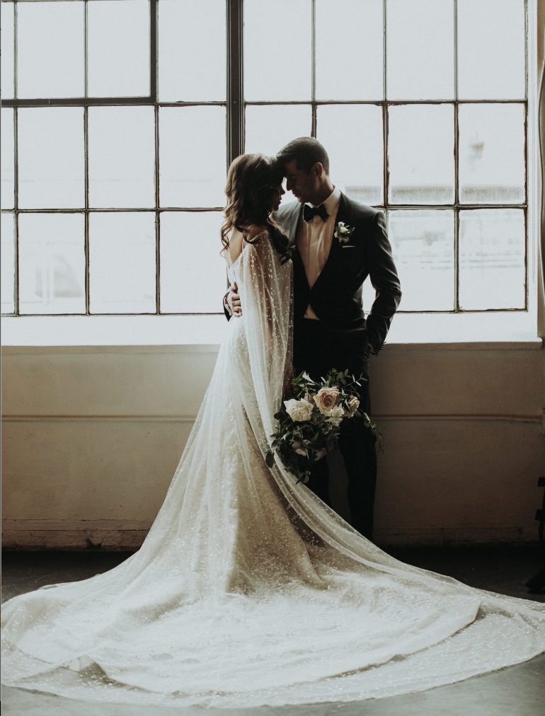 A lace A line wedding dress paired with a gorgeous fully embellished sheer capelet with a train for a glam and chic look