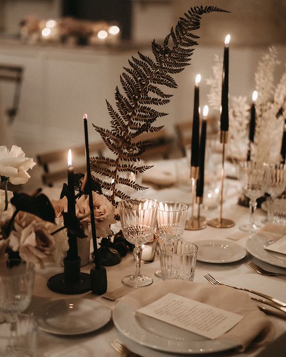 a lovely cluster wedding centerpiece of black candles, dried leaves and white roses is a very stylish idea to rock at a refined modern wedding