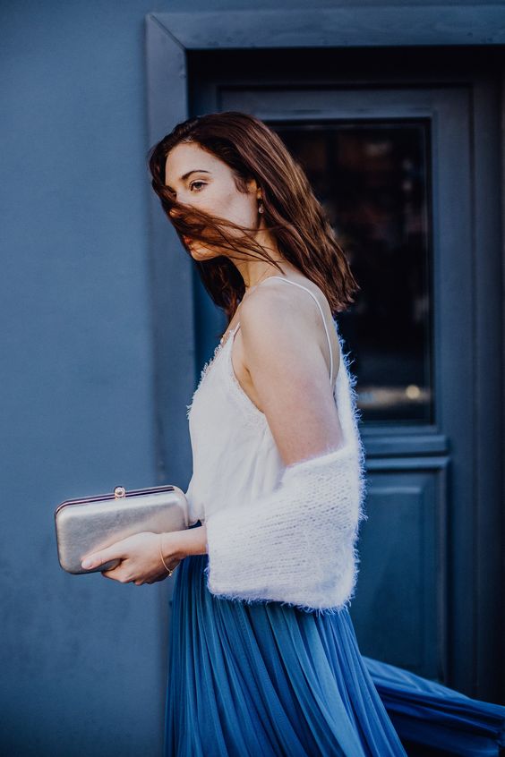a lovely winter casual bridal look with a white top, a white knit coverup, a bold blue pleated skirt and a silver clutch is wow