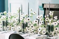 a lush and beautiful black and white wedding centerpiece of anemones, tall and thin black candles is a fresh take on classics