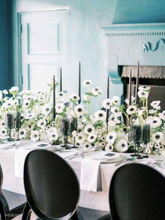 a lush and beautiful black and white wedding centerpiece of anemones, tall and thin black candles is a fresh take on classics