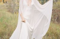 a minimalist bridal look with a slip silk maxi wedding dress wiht a train and a modern sheer capelet that accents the look and makes it wow