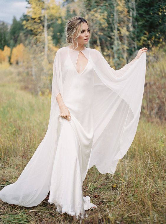 a minimalist bridal look with a slip silk maxi wedding dress wiht a train and a modern sheer capelet that accents the look and makes it wow
