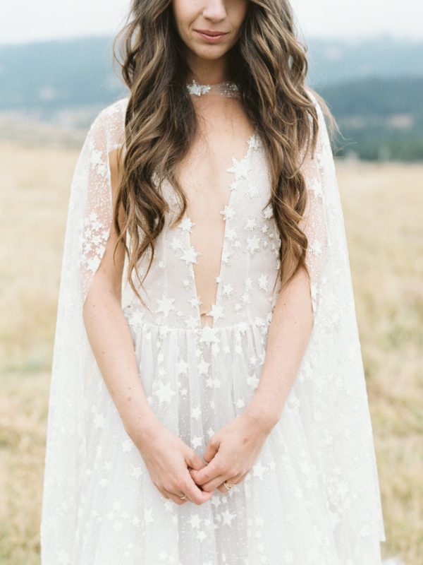 a neutral star applique wedding dress with a plunging neckline and a capelet that matches and accents the outfit even more