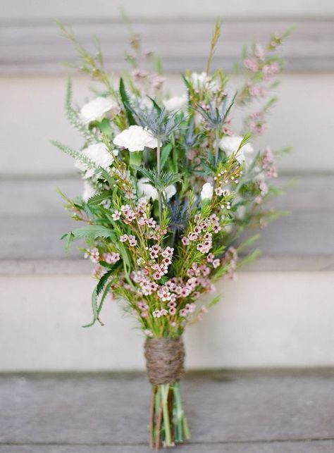 a relaxed and laid-back wedding bouquet of waxflower, white blooms, thistles and greenery wrapped with yarn is amazing for a boho bride