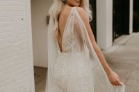 a sexy lace mermaid wedding dress with a cutout back and a sheer capelet to make more impact and leave a longer impression