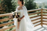 a sexy strapless A-line wedding dress with a corset and a train plus a flowy semi sheer capelet that gives a soft feel to the look
