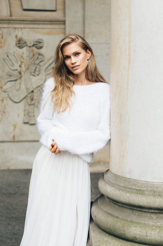 a simple and beautiful winter bridal look with a fuzzy white sweater with a bateau neckline and a tulle maxi skirt plus delicate earrings