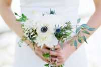 a small and delicate wedding bouquet of white anemones, peonies, thistles, greenery and berries is a chic and stylish idea for spring or summer