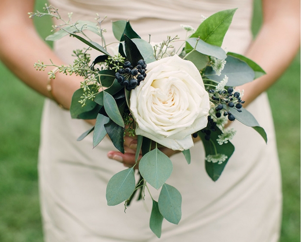a small wedding bouquet of a white rose, berries and greenery is a delicate and chic idea for a spring or summer wedding