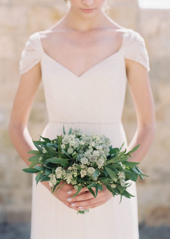 a small wedding bouquet of leaves and thiny white buds is a very delicate and fresh idea for a spring or summer bride