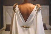 an ultra-modern and glam plain white capelet with gold embellishments on the shoulders and back and a cutout back