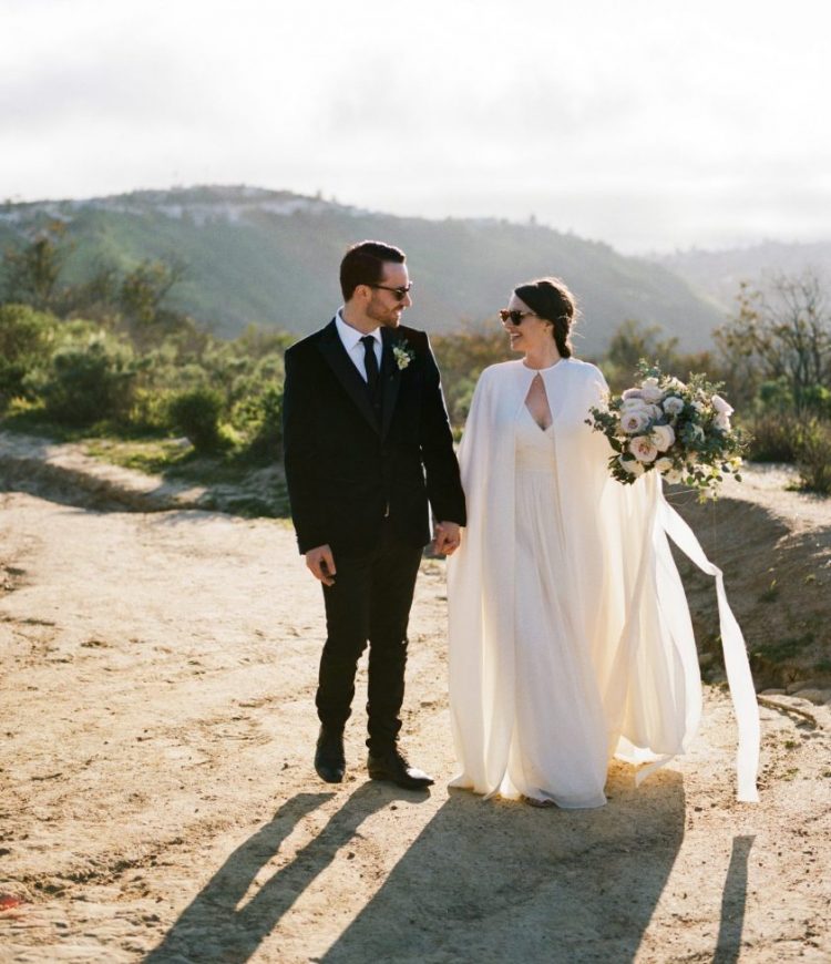 an ultra-modern bridal look with a plain A-line wedding dress with a deep V-neckline and a matching semi sheer plain capelet for a bolder statement