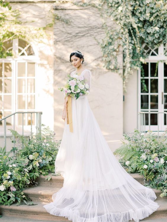 a Bridgerton-inspired bridal look with an A-line wedding dress with semi sheer sleeves, a square neckline and a skirt with a train