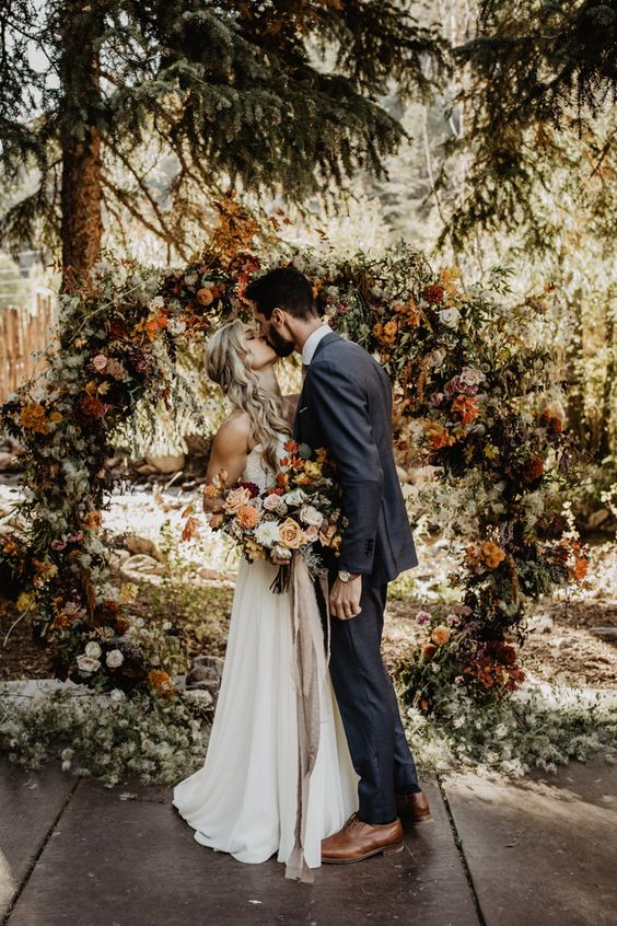 a lovely round earthy-tone wedding arch with lush florals and greenery plus twigs is a beautiful idea to rock