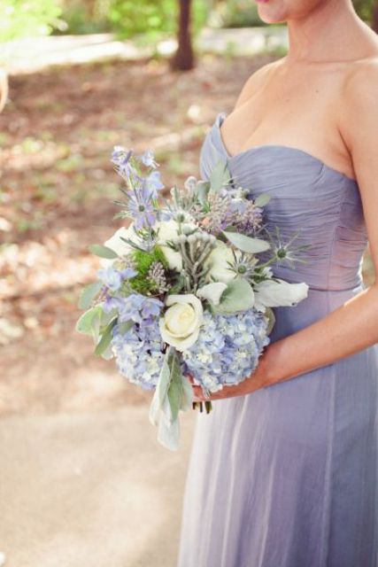 a strapless periwinkle maxi bridesmaid dress with a draped bodice, a neutral and periwinkle wedding bouquet with thistles and greenery
