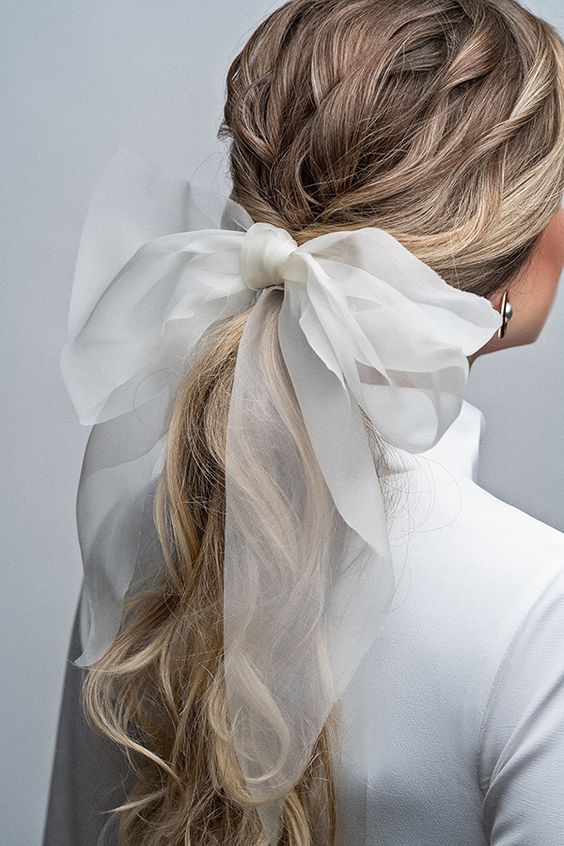 a twisted low ponytail accented with a large bow is a very glam and fresh idea for a modern bride