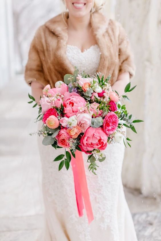 a coral charm peony, pink rose, blush garden rose, and coral ranunculus wedding bouquet with greenery and ribbons for a winter wedding