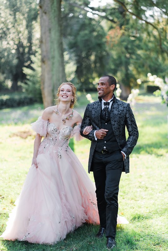 the couple dressed in attire inspired by Bridgertons - a chic take on a black morning suit and a blush off the shoulder wedding dress with floral embroidery