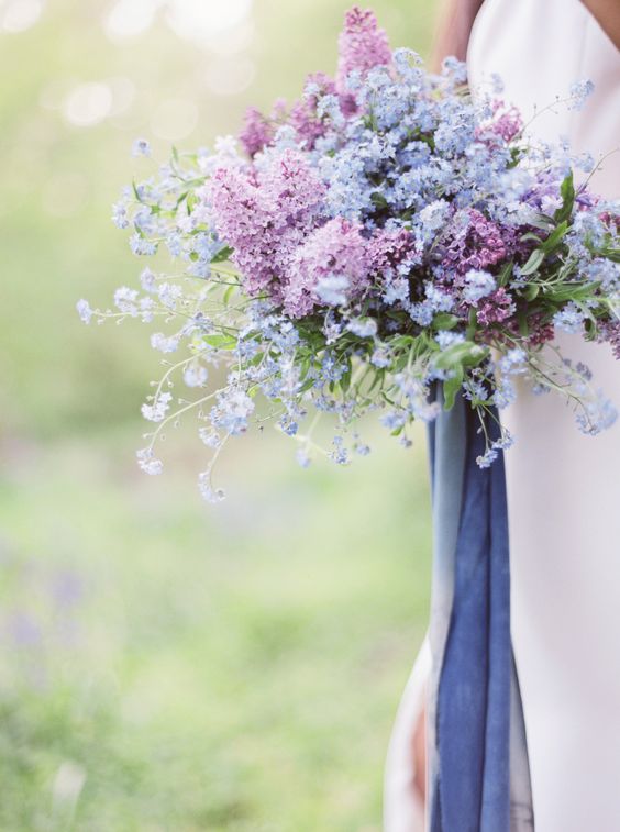 a beautiful and lush wedding bouquet of lilac and perinwinkle blooms plus matching long ribbons is an amazing idea for spring