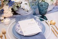 12 a beautiful tablescape with a periwinkle table runner, napkin and a plate, with a lush floral centerpiece of neutral and periwinkle flowers
