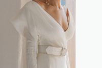 13 a gorgeous modern wedding dress with a V-neckline, long sleeves, accented shoulders, a white leather belt, a long veil and baroque pearls for a 90s inspired look