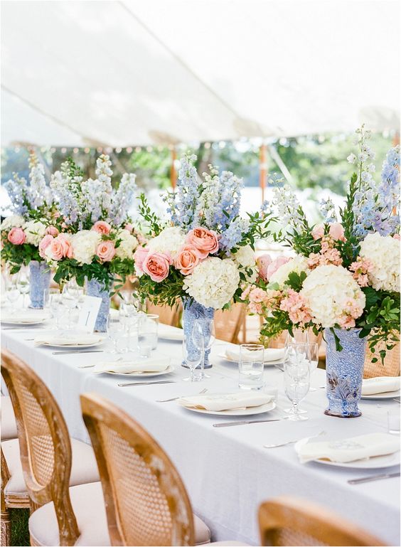 a chic and classic wedding tablescape with neutral linens, periwinkle vases with periwinkle, pink and neutral blooms and greenery