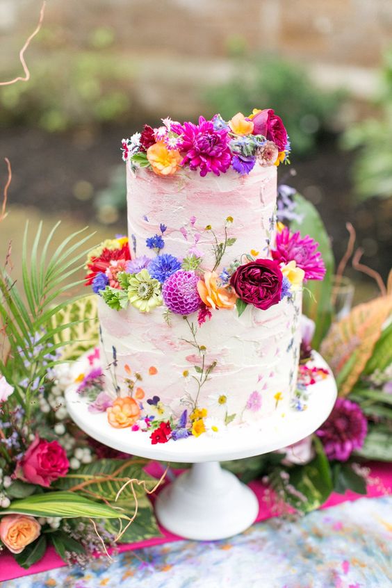 a pink and white textural buttercream wedding cake with bold florals all over for a summer festival or boho wedding