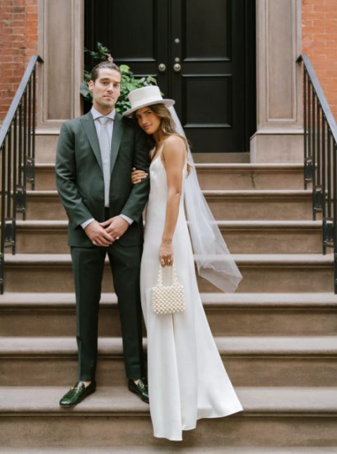 a slip maxi wedding dress, a white hat with a veil attached and an embellished bag for a modern and 90s inspired bridal look