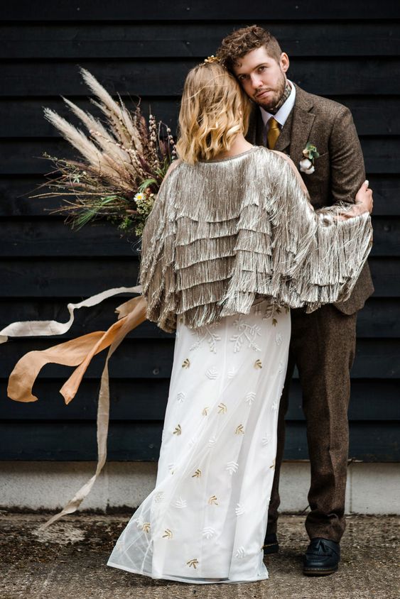a unique bridal jacket fully covered with long grey fringe in tiers on the back is a gorgeous idea for a boho wedding