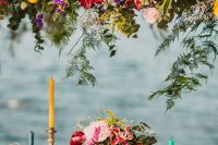 15 a super bright wedding reception with bold florals and greenery over the table and on the table, colorful candles and glasses