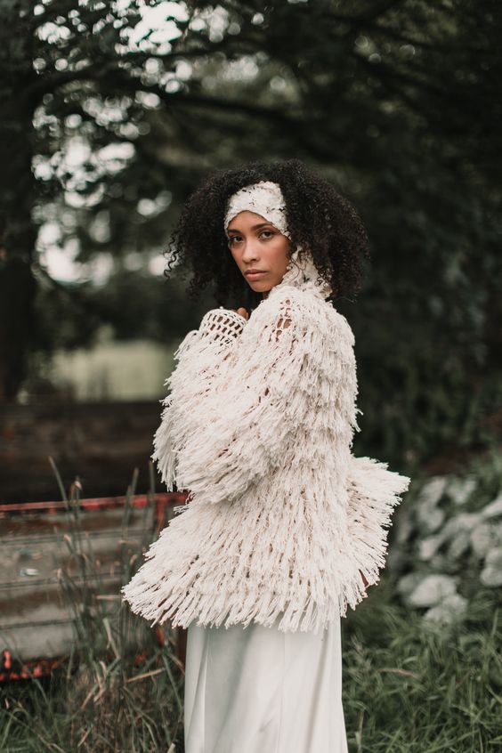 a unique white crochet  bridal jacket fully covered with fringe and tassels is ideal to accessorize a boho bridal look