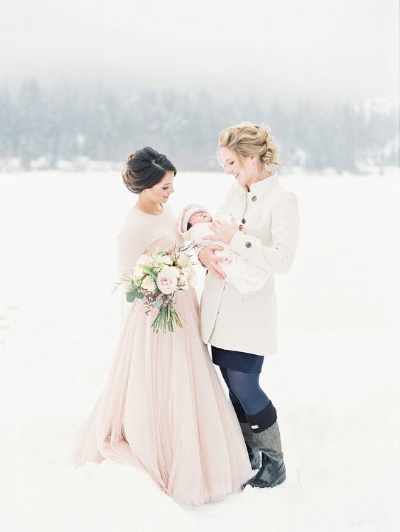 a pink wedding dress with a layered full skirt plus a matching pink jumper over the dress to keep the bride warm in the snow