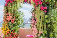 16 a super vibrant and lush wedding arch decorated with greenery, yellow, red, light and hot pink blooms is wow