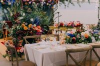 17 a gorgeous colorful wedding reception space with greenery and super bold blooms all over the space and string lights over it