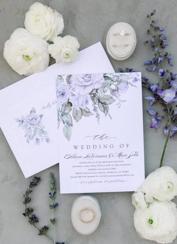 a delicate wedding invitation suite with hand-painted very peri blooms and greenery plus calligraphy for a delicate look