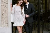 18 a lace high neckline wedding dress with long sleeves and a ruffled skirt is covered with a white jacket and modern lace up shoes